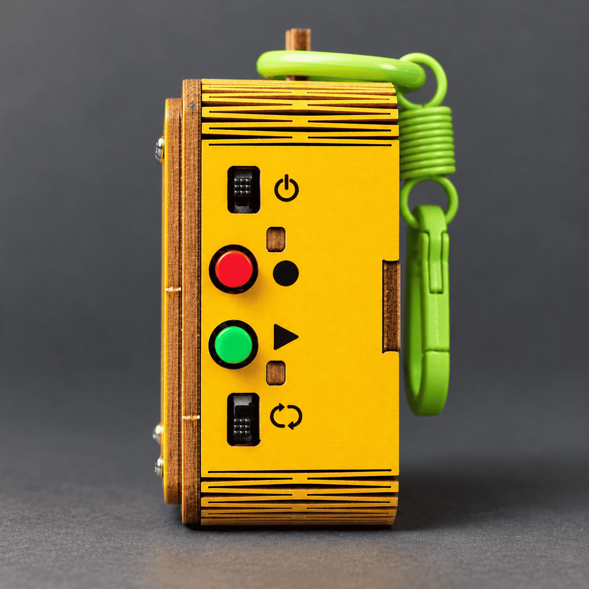 Side view of yellow emoji voice recorder with green loop strap and colored control buttons
