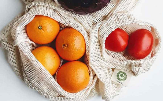 Cotton mesh produce bag with drawstring, filled with oranges in a net pouch