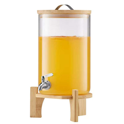 Lower view of clear glass beverage dispenser with bamboo stand and metal spigot tap