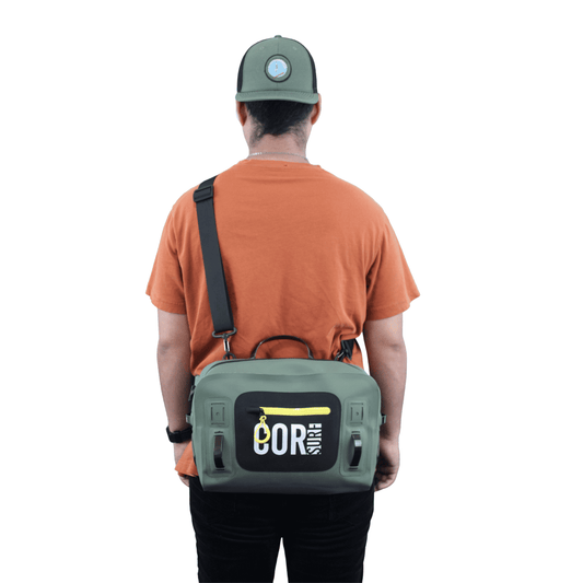 Waterproof lumbar pack in olive green with black straps, worn on a model, back view.