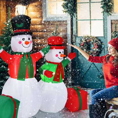 Inflatable snowman pair with gift boxes beside a seated person