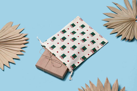 Cotton gift bags with festive gift print, drawstring ties over kraft box