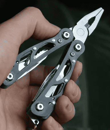 Handheld multi-tool pliers with blade and bit, black and silver, in use
