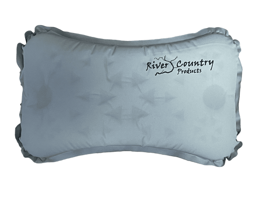 Self-inflating camping pillow, light blue-gray, soft rounded shape with carry tabs