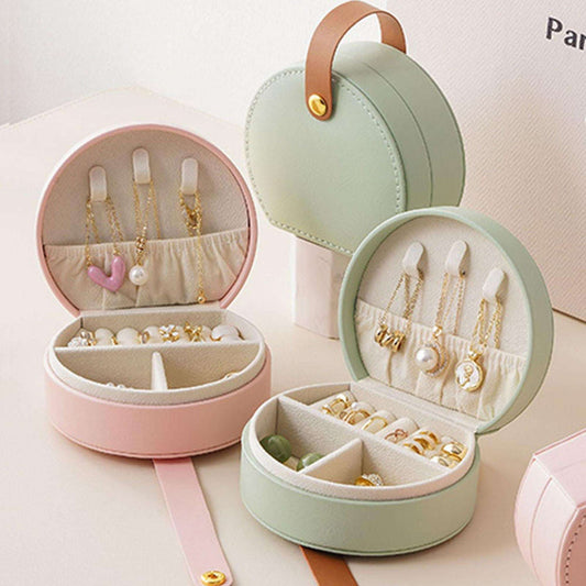 Mint green round travel jewelry storage case with open compartments and ring/necklace slots
