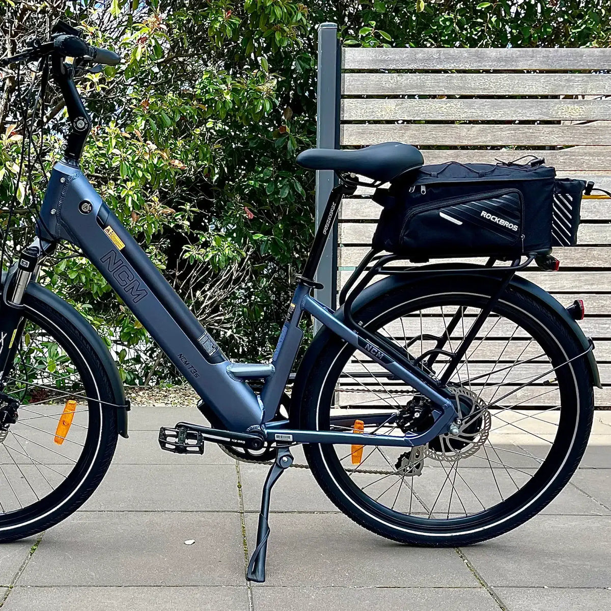 Black bike rack bag mounted on rear rack of blue bicycle with top flap
