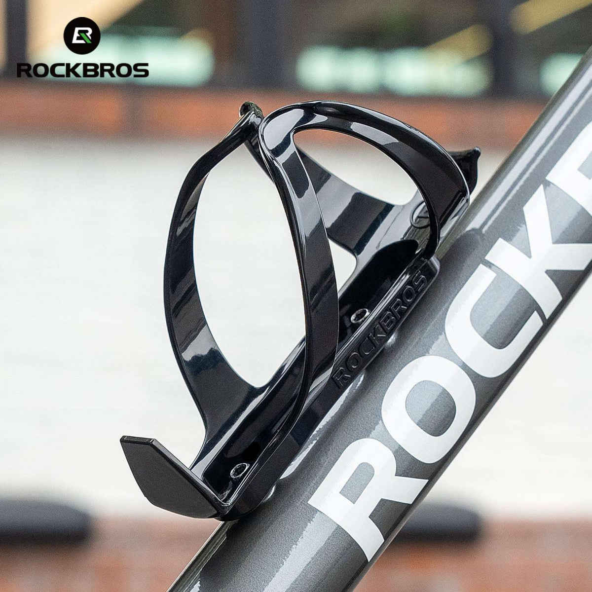 Bicycle water bottle cage, glossy black plastic mounted on a bike frame tube.