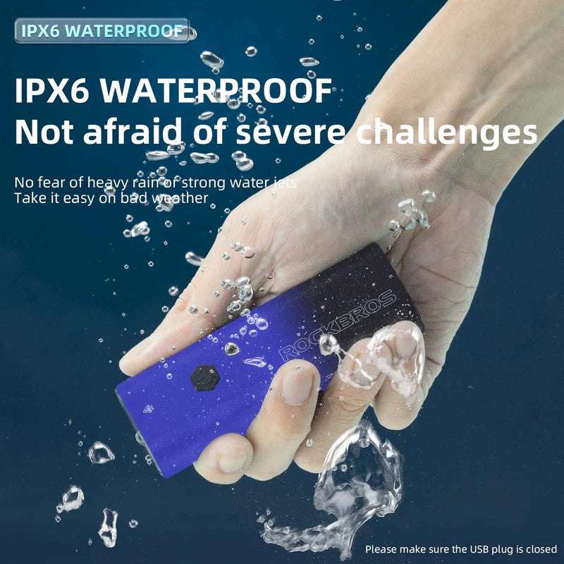 Waterproof front bike light held in a hand with water droplets on the surface