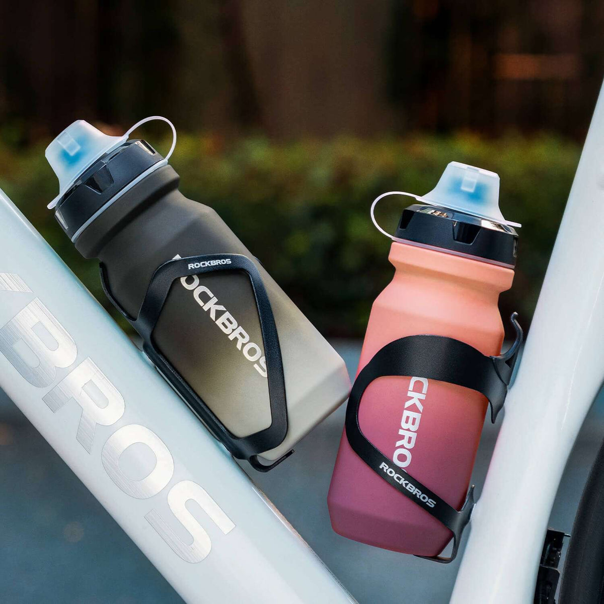 Bike water bottles in bottle holders: gray and pink with flip-top lids