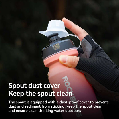 Black bike water bottle with dust-proof spout cover, held in a hand