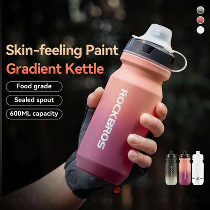 Hand holding pink-to-purple gradient bike water bottle with black lid and sealed spout