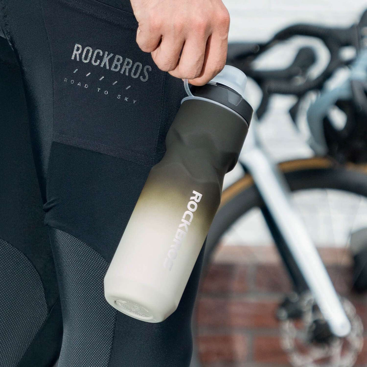 Gray bike water bottle with black spout lid, held upright