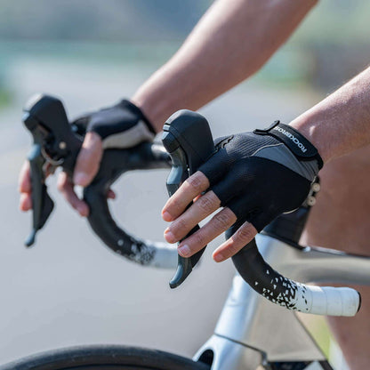 Half-finger cycling gloves on a rider hand, black mesh fabric with padded knuckles.