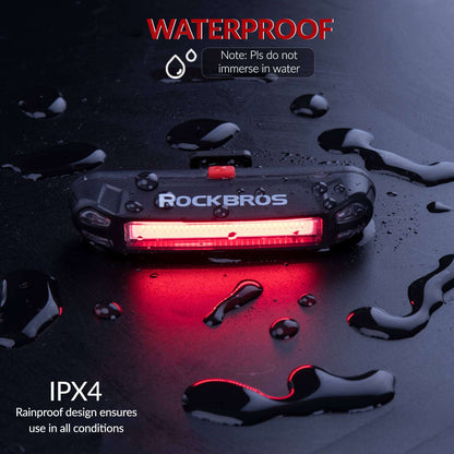 Water-resistant rear bike light with red glow, shown with water droplets