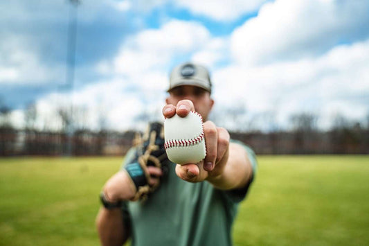 White baseball with red stitching held by a baseball player’s hand