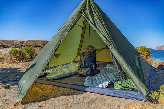 Green tent interior with mesh walls, sleeping pads, and backpack on the floor