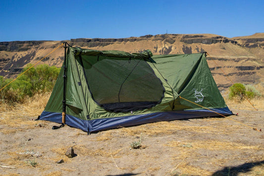 1-person trekking pole tent with dark green fly and mesh front door, blue ground skirt